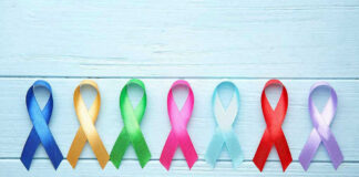 Colorful awareness ribbons on light wooden background