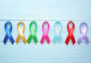 Colorful awareness ribbons on light wooden background