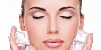 A woman with closed eyes holding ice cubes against her face