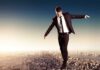 Businessman walking on a tightrope above a city skyline