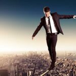 Businessman walking on a tightrope above a city skyline