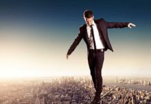 Businessman walking on a tightrope above a city skyline
