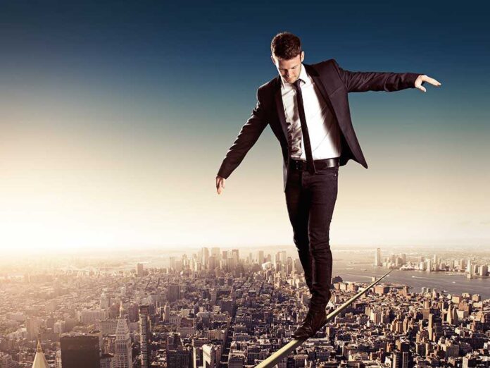 shutterstock_194422361.jpg Businessman walking on a tightrope above a city skyline