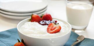 A bowl of creamy dessert topped with fresh strawberries and a drizzle of jam