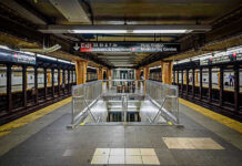 Subway station platform with directional signs overhead.