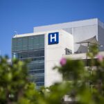 HORRIFYING — Body Found in Hospital Water Tank Modern hospital building with a prominent H sign against a clear blue sky