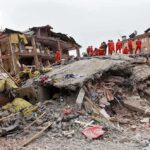 California’s “Big One” Looming? — Everyone is Paying Attention Rescue workers in orange uniforms on a collapsed building site after an earthquake