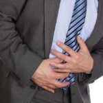 Businessman in a suit holding his stomach, appearing to be in discomfort