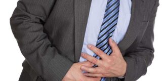 Businessman in a suit holding his stomach, appearing to be in discomfort