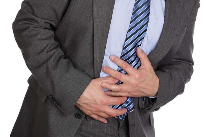 Businessman in a suit holding his stomach, appearing to be in discomfort