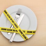 A plate with a fork and knife wrapped in yellow crime scene tape