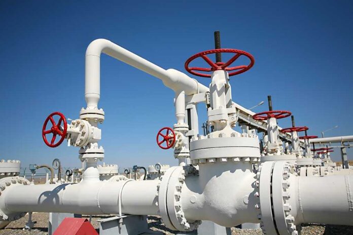 Industrial pipeline with red valves against a clear blue sky