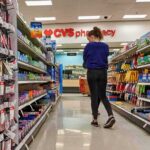 A person shopping in a CVS pharmacy aisle filled with various products