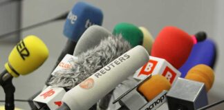 A collection of various microphones arranged for a press conference
