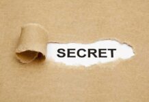 A torn piece of brown paper revealing the word SECRET underneath