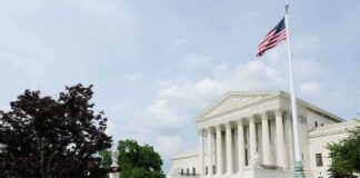 The U.S. Supreme Court building with an American flag and landscaped grounds