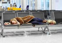 A traveler sleeping on a bench in an airport waiting area