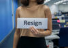 Person holding a sign that says resign