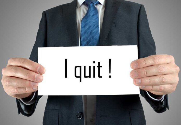 A man in a suit holding a sign that says I quit