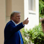 Man in suit giving thumbs up.
