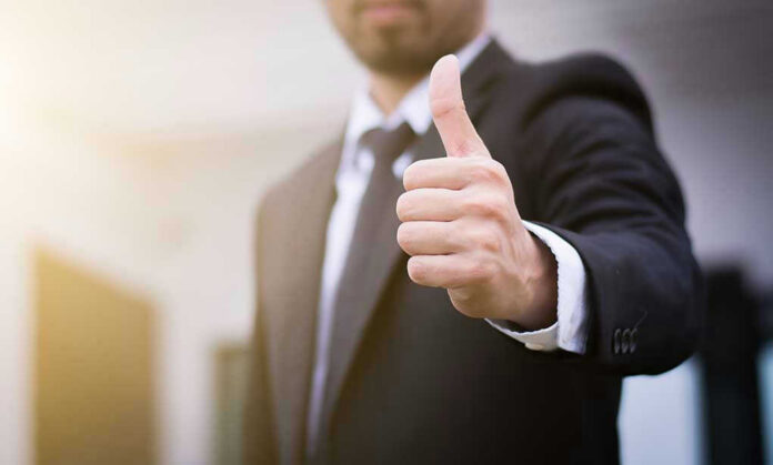 Person in suit giving thumbs up gesture.