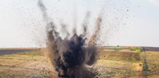 A large explosion creating a dark smoke cloud in a rural landscape