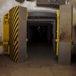 Entrance to an underground bunker with large heavy doors and a sign