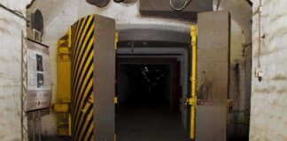 Entrance to an underground bunker with large heavy doors and a sign