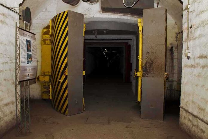 Entrance to an underground bunker with large heavy doors and a sign