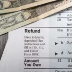 Close-up of tax refund form with cash on a wooden surface