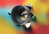 Camera lens protruding through a colorful background