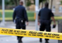 Police officers walking past caution tape at a crime scene