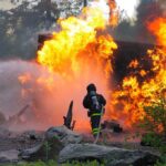 Family of Seven VANISHES in Fiery Explosion Firefighter battling a large fire with water spray