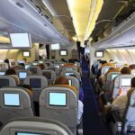 EMERGENCY Mid-Air Birth—Shoelace Saves Baby Interior view of an airplane with passengers seated and using in-flight entertainment screens