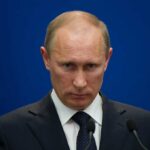 Russia Publishes European Addresses—Then Threatens Strikes A serious-looking man in a suit at a press conference with a blue background
