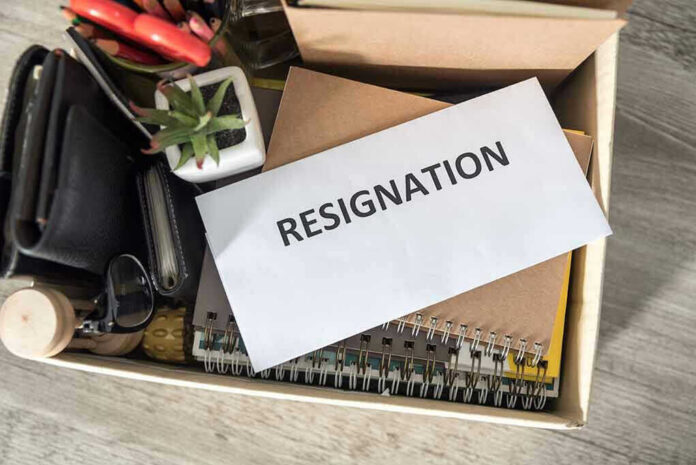 Envelope labeled RESIGNATION atop office supplies in box.