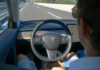 Person using autopilot in Tesla on highway.