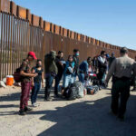 Border patrol agents interact with a group of people.