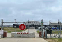 Chain-link fence with Restricted Area Stop No Photography sign.