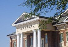 California Mayor EXPOSED as Chinese Agent! Exterior view of a city hall building with columns and a clear blue sky