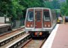 Metro train arriving at a station surrounded by greenery