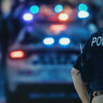 Allegations in Texas Bar Attack Fuel Calls for Answers Police officer with patrol car and flashing lights.