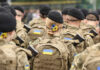 Soldiers in camouflage uniforms with Ukrainian flags.