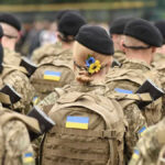 Soldiers in camouflage uniforms with Ukrainian flags.