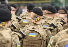 Soldiers in camouflage uniforms with Ukrainian flags.