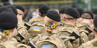 Soldiers in camouflage uniforms with Ukrainian flags.