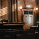War Secrets at Home: A Classified Email Scandal Rocks National Security World Empty courtroom with judges bench and wooden decor.