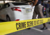 Crime scene tape blocking off white sedan.