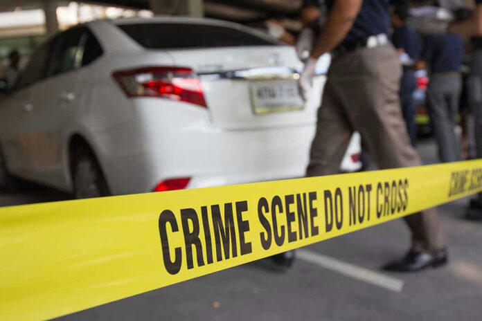 351048443 Crime scene tape blocking off white sedan.