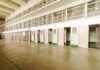 Interior view of a prison cell block with empty cells and security bars